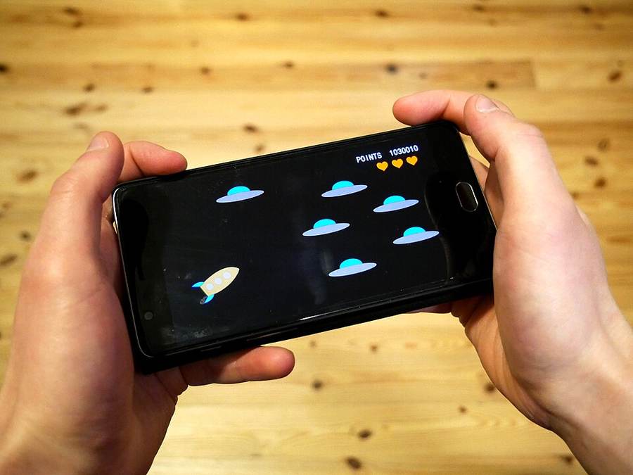 Seseorang bermain game melalui ponsel, ilustrasi pengalaman mobile Shopeeslot