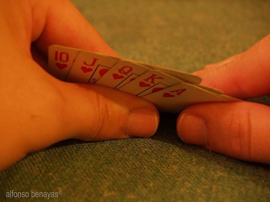 Tangan memegang kartu poker royal flush hati